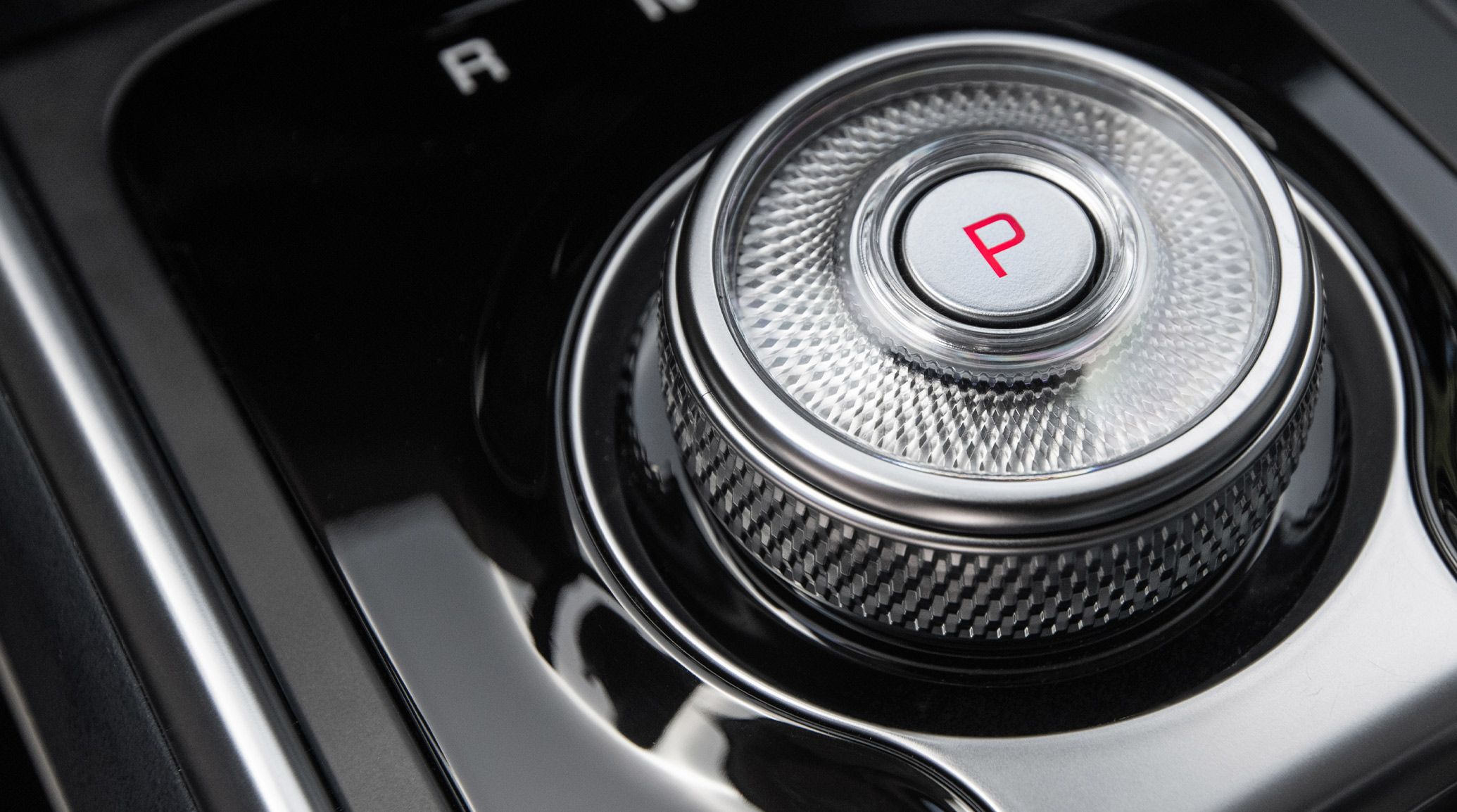 A close-up shot of the 2027 Kia Carnival MPV Hybrid rotary gear selector dial shows its textured finish and modern push-button transmission design.