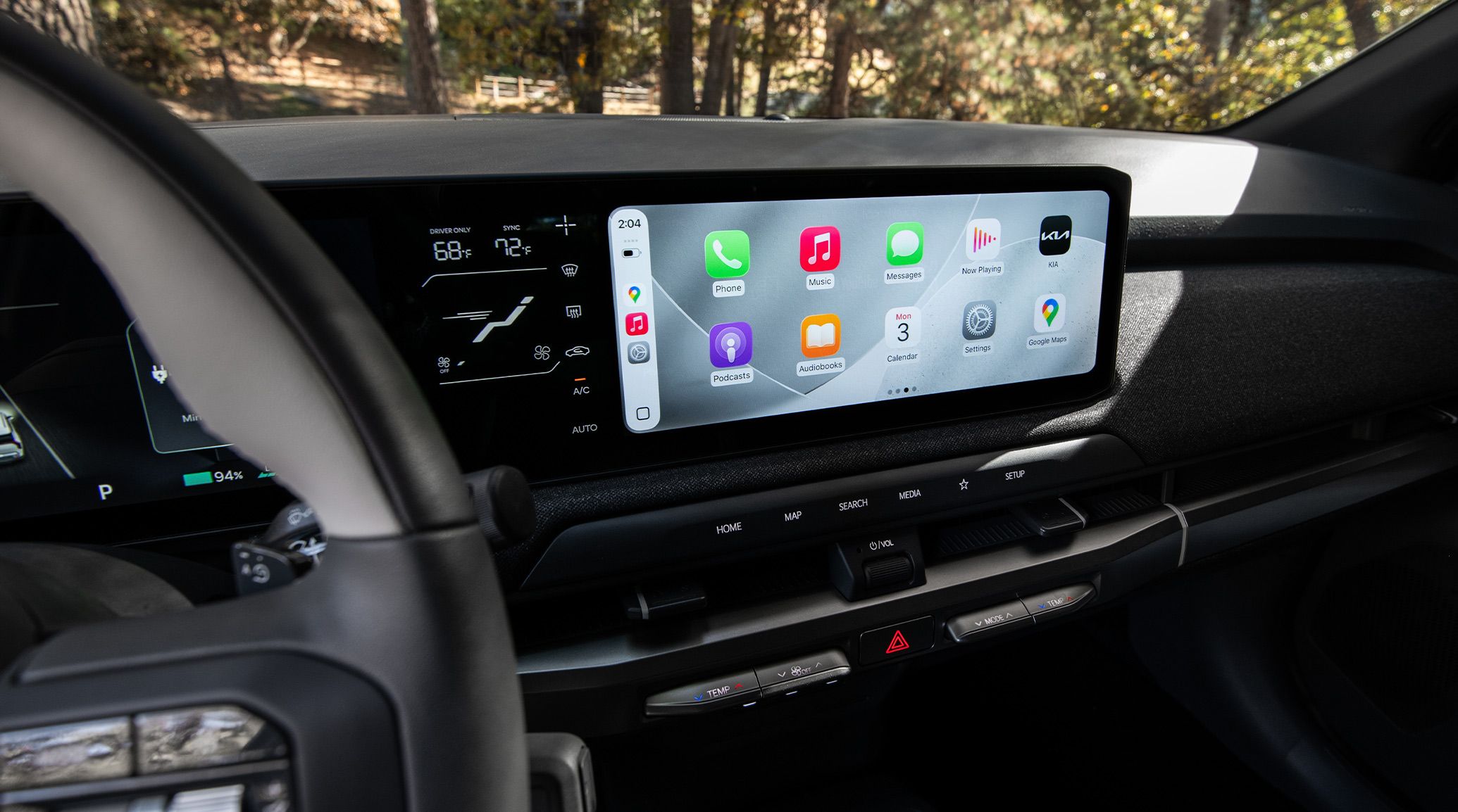 Close-up view of the digital display inside the 2027 Kia EV3 compact electric SUV, showing temperature controls, date and time, apps, maps, console buttons, and more.