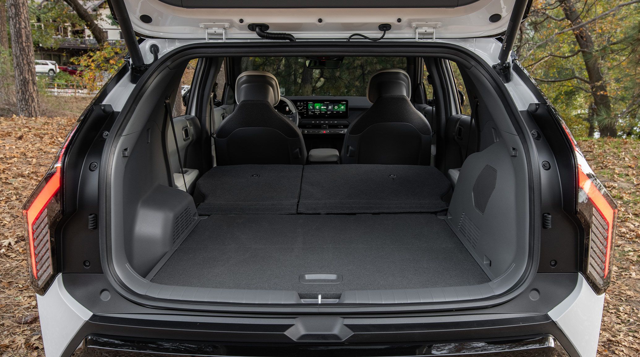 Rear photograph of the 2027 Kia EV3 compact electric SUV with the trunk wide open, showing the spacious rear cargo room available when the back row of seats is folded downward.