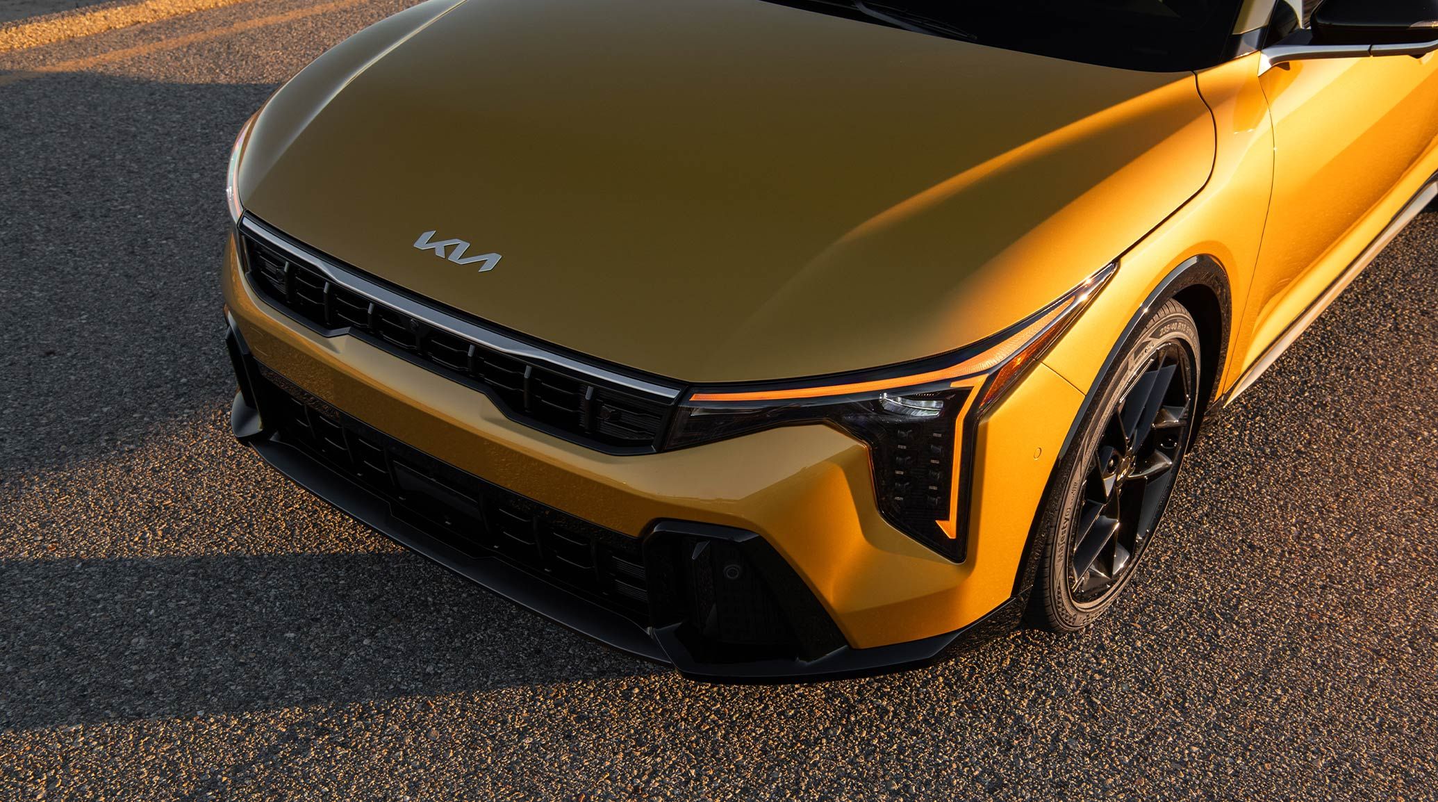 Standing Shot of the 2026 K4 Hatchback GT-Line Turbo in Yellow as the sun goes down, accentuating the Amber Daytime Running Lights (DRL's).