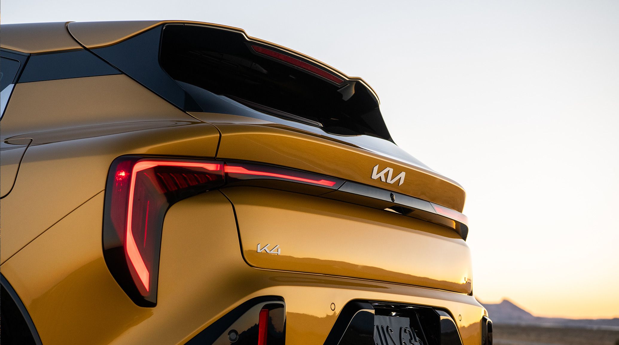 Exterior Standing Shot for the 2026 K4 Hatchback GT-Line Turbo in Gold Yellow, displaying the LED Taillights.