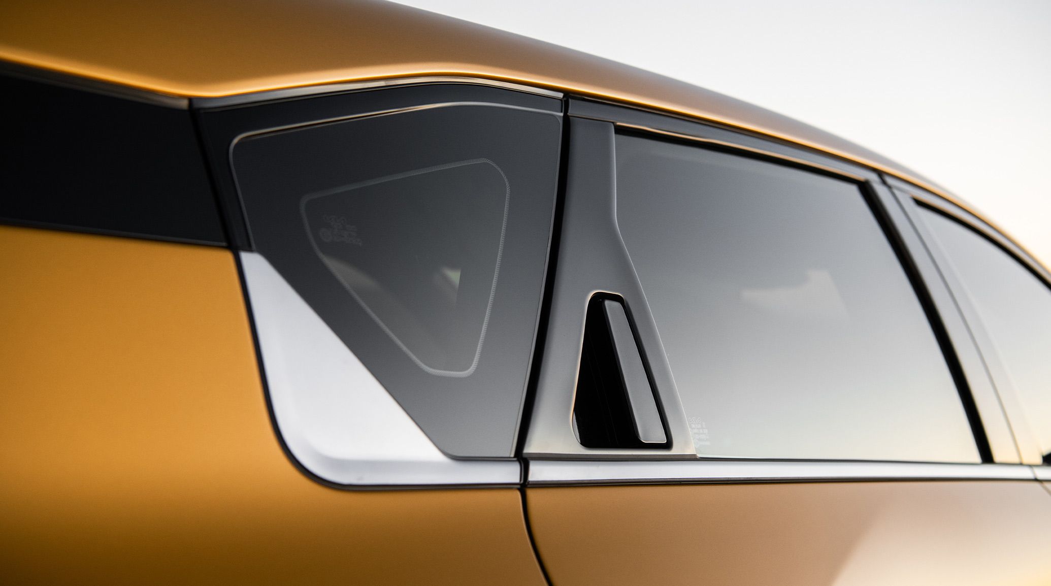A close-up exterior shot of the 2026 K4 Hatchback GT-Line Turbo in Gold Yellow, focusing on how the hidden rear door handles are integrated within the C-Pillar of the vehicle.