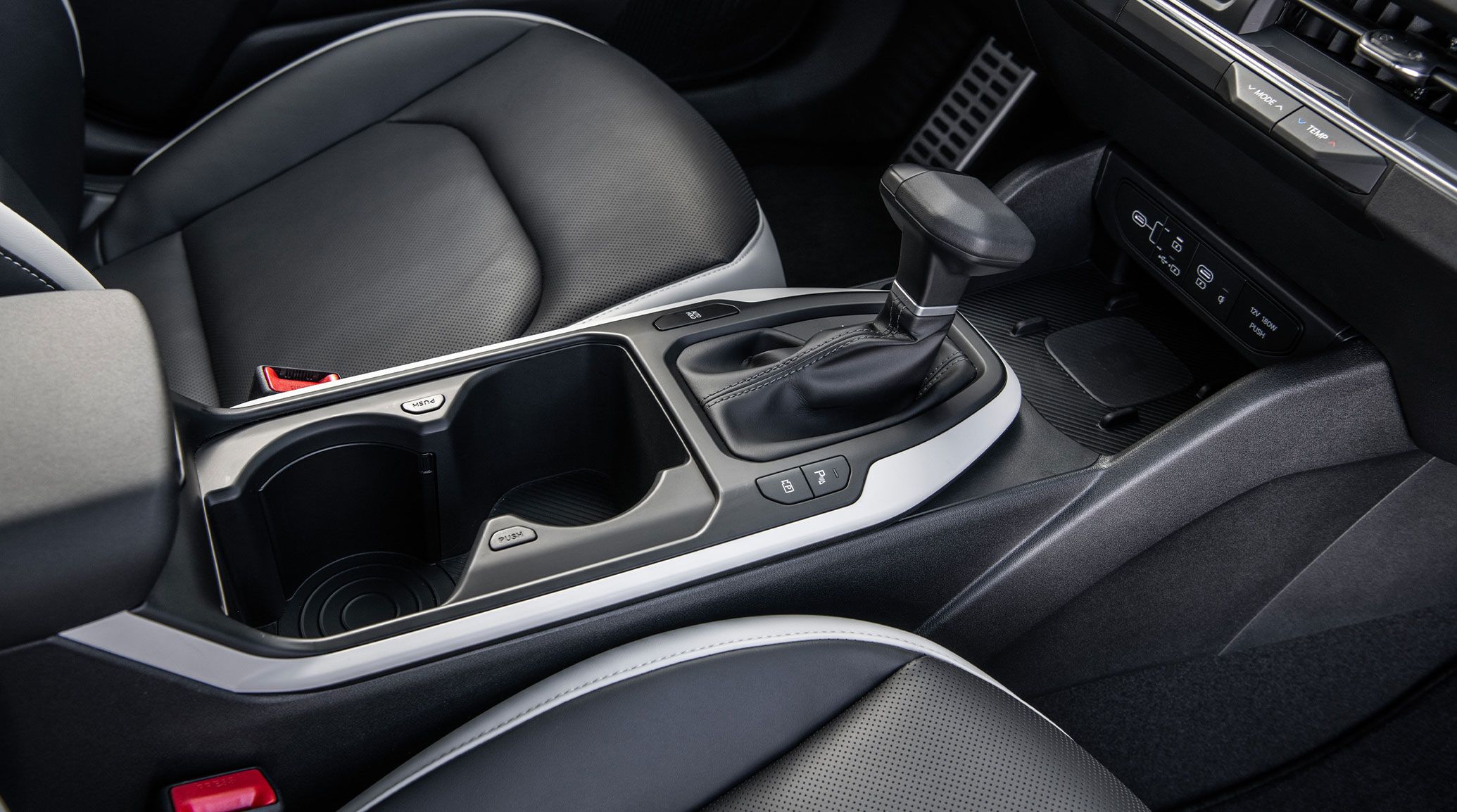 An interior shot of the center console view of the 2026 K4 Hatchback GT-Line Turbo highlighting the large, adjustable cup holders and wireless charging pad.