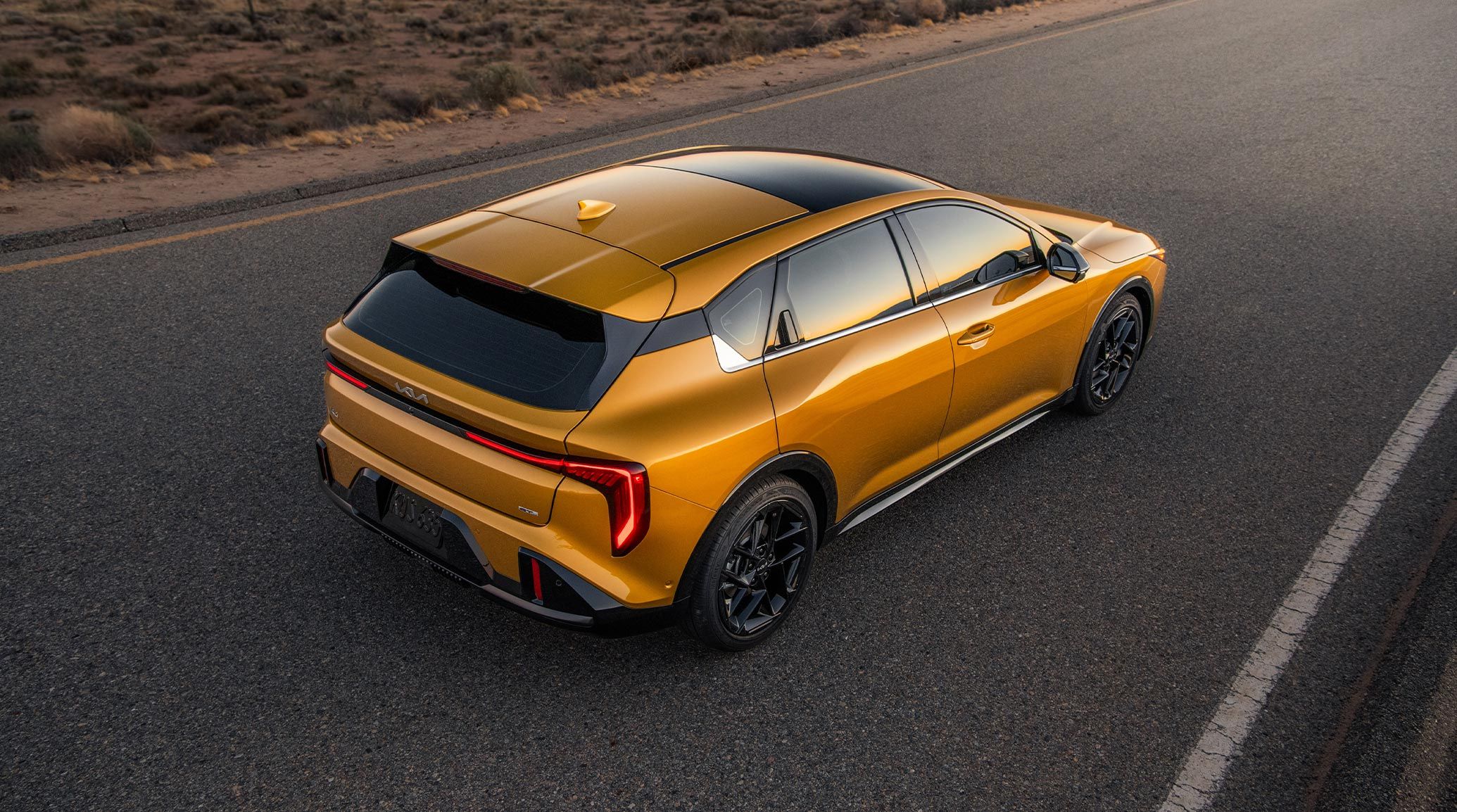 A top down shot of the 2026 K4 Hatchback GT-Line Turbo in Golden Yellow  in the desert landscape with a focus on the Ultra-Wide Sunroof.