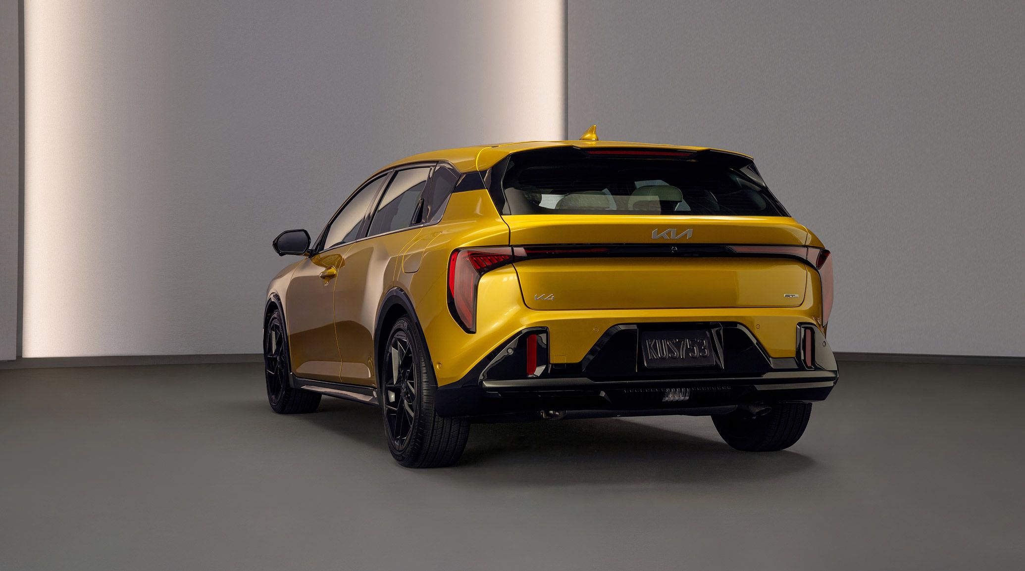 A rear-view image of the 2026 K4 Hatchback in yellow parked in a white room with ambient lighting. The vehicle has gloss black tires and a sleek hatchback design, highlighting the spacious cargo area.