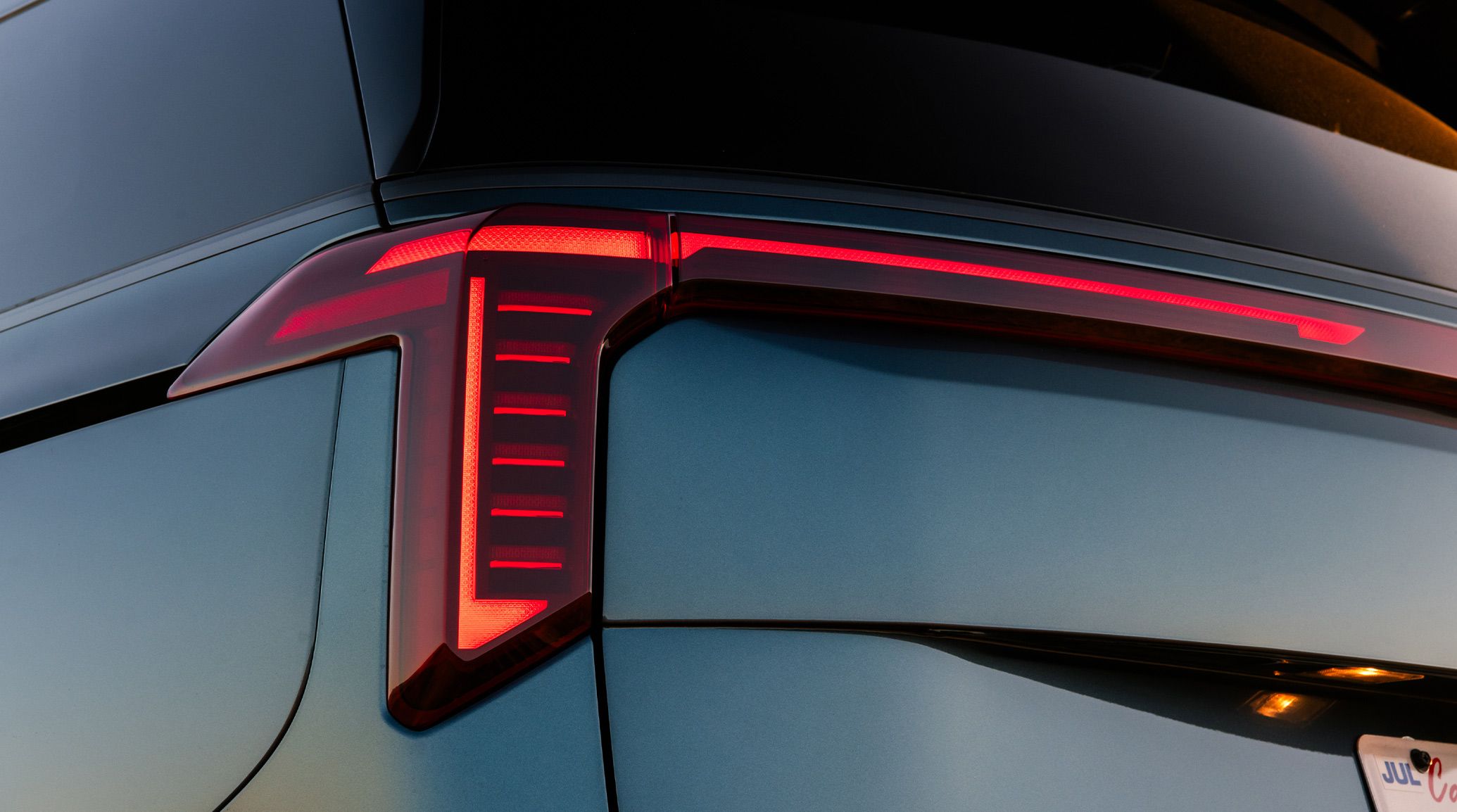 A close-up shot of the 2027 Kia Carnival MPV in blue, focusing on the LED taillights with a star map design.