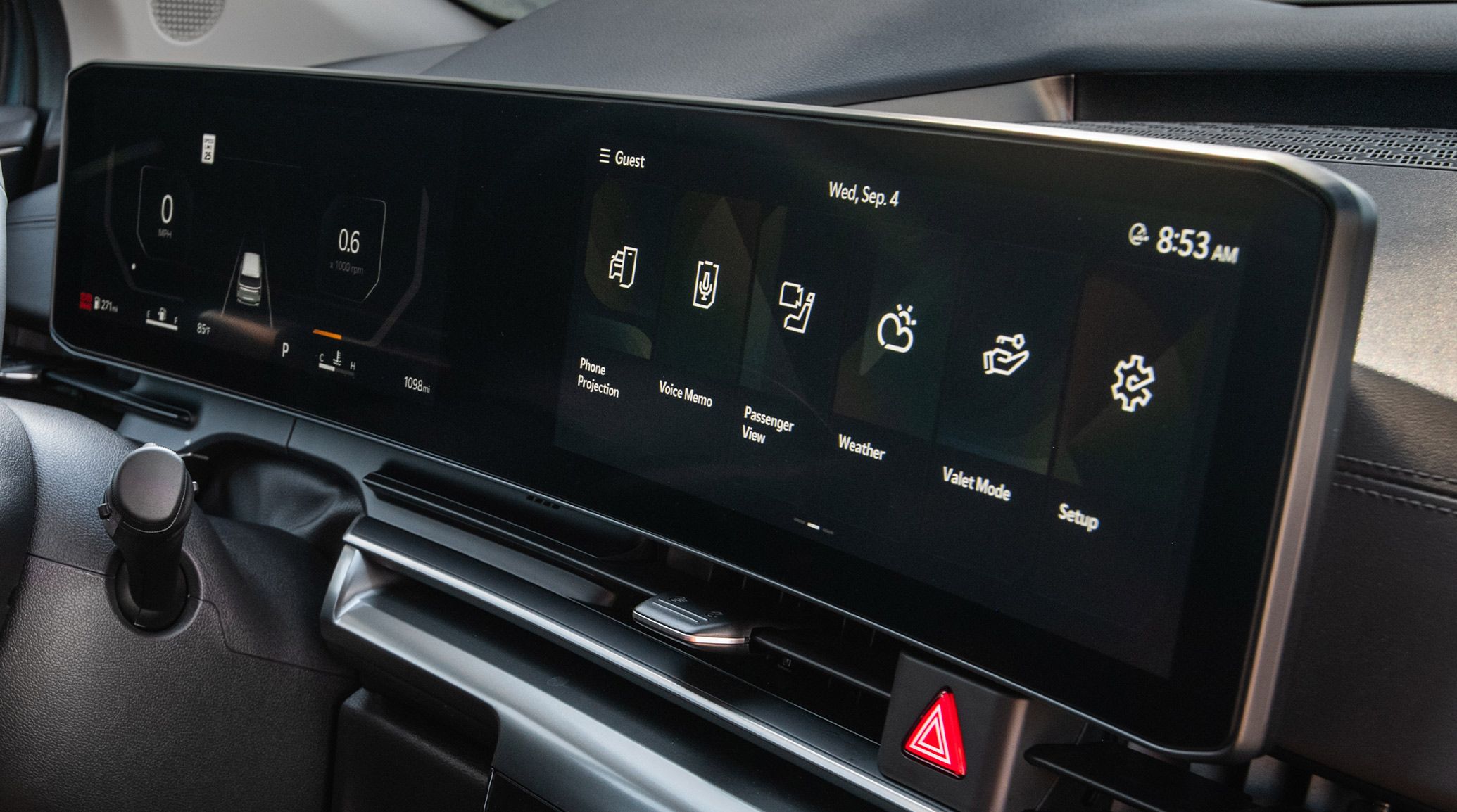 A close-up shot of the 2027 Kia Carnival MPV interior features a wide digital display in black with navigation and vehicle controls integrated into a sleek dashboard layout.
