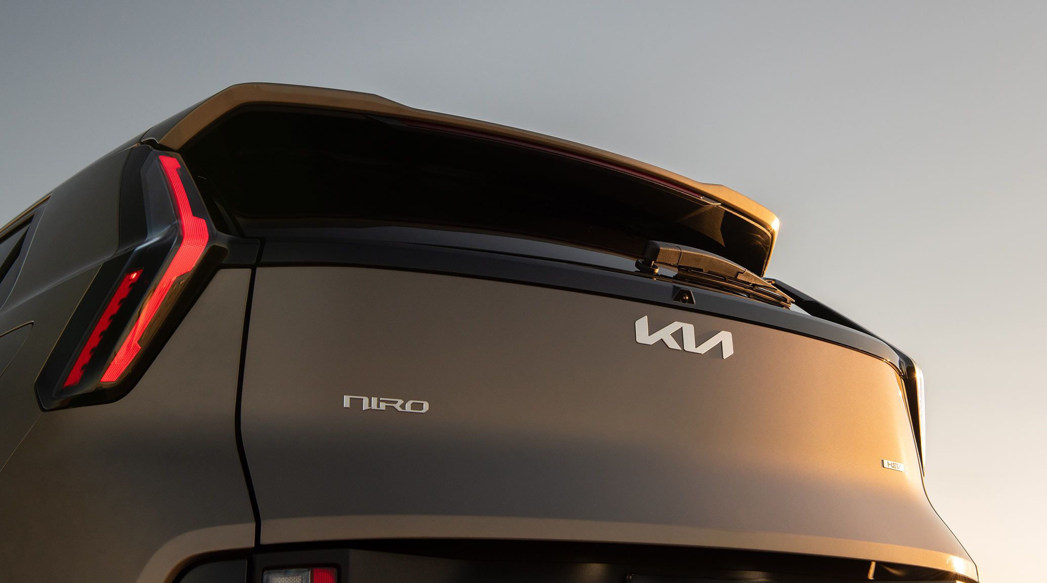 Low-angle rear photograph of the 2027 Kia Niro Hybrid Electric SUV showcasing the Kia, Niro, and HEV logos on the back of the trunk door.