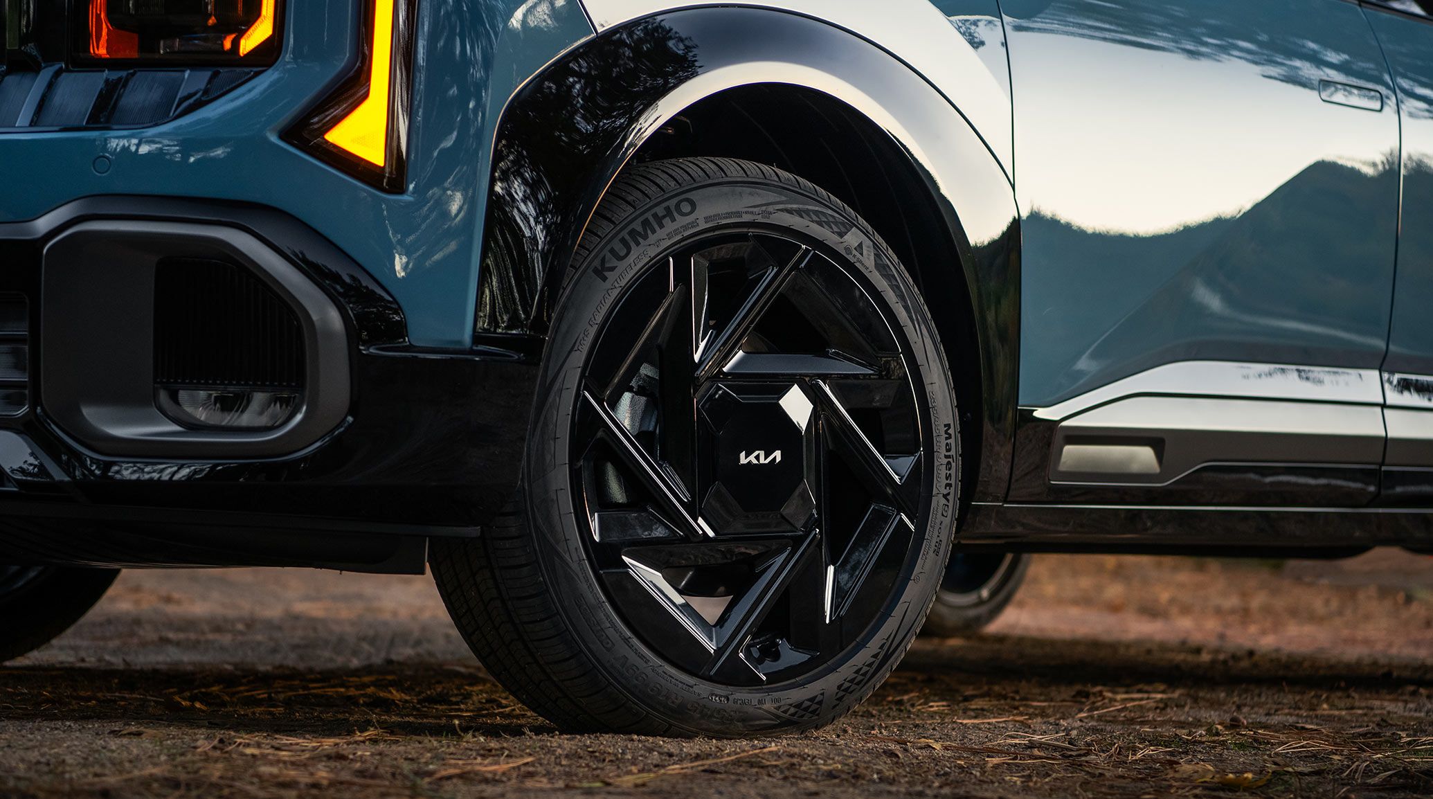 Zoomed-in shot of the 2027 Kia Seltos in blue, highlighting the exclusive, gloss black 19-in wheels on the X-Line SX AWD. The SUV is parked on a dirt road.