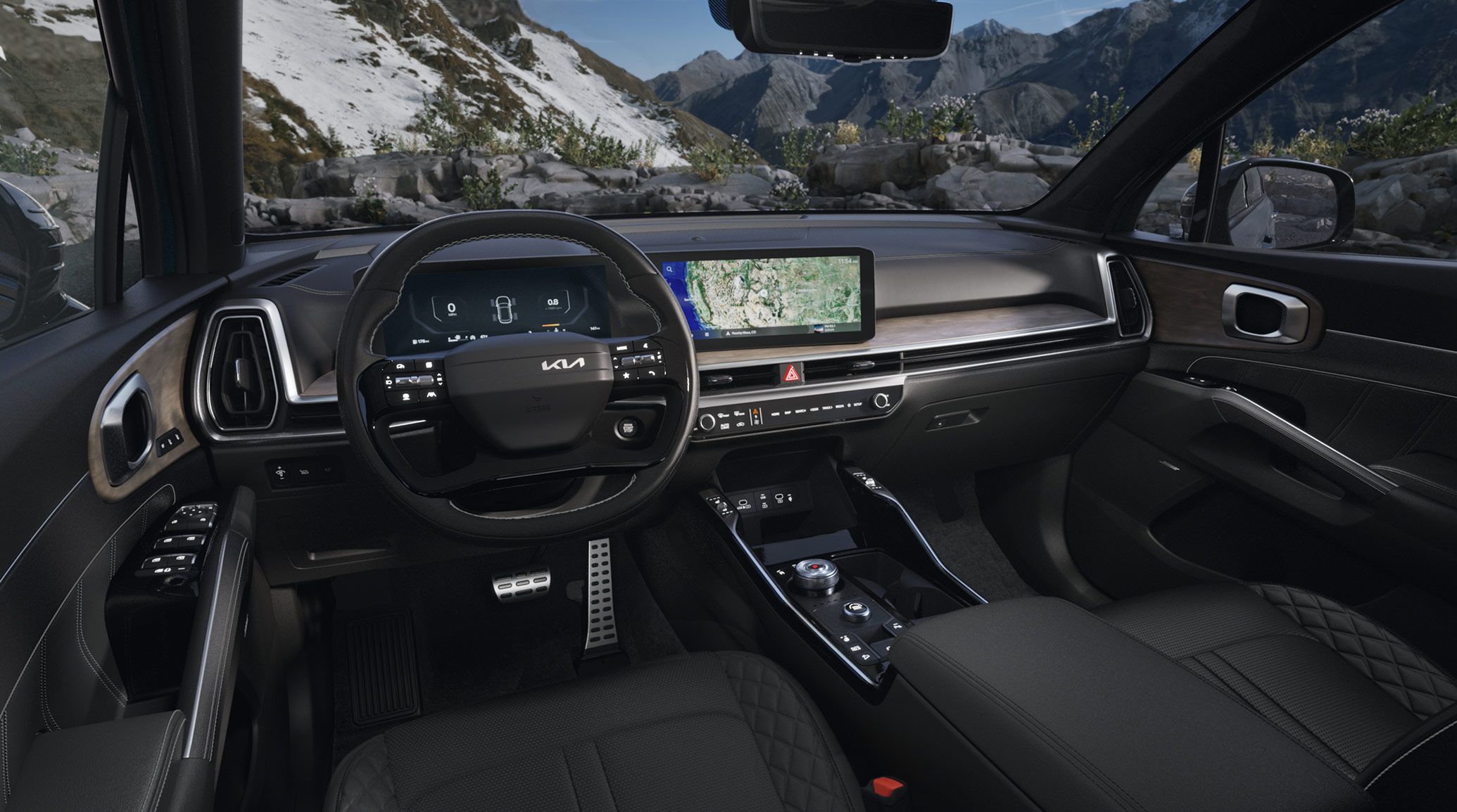 Interior wide-angle photo of the 2027 Kia Sorento Hybrid SUV showing the dashboard, steering wheel, center console, seats, and other front details. A snowy mountain slope is visible through the windshield.
