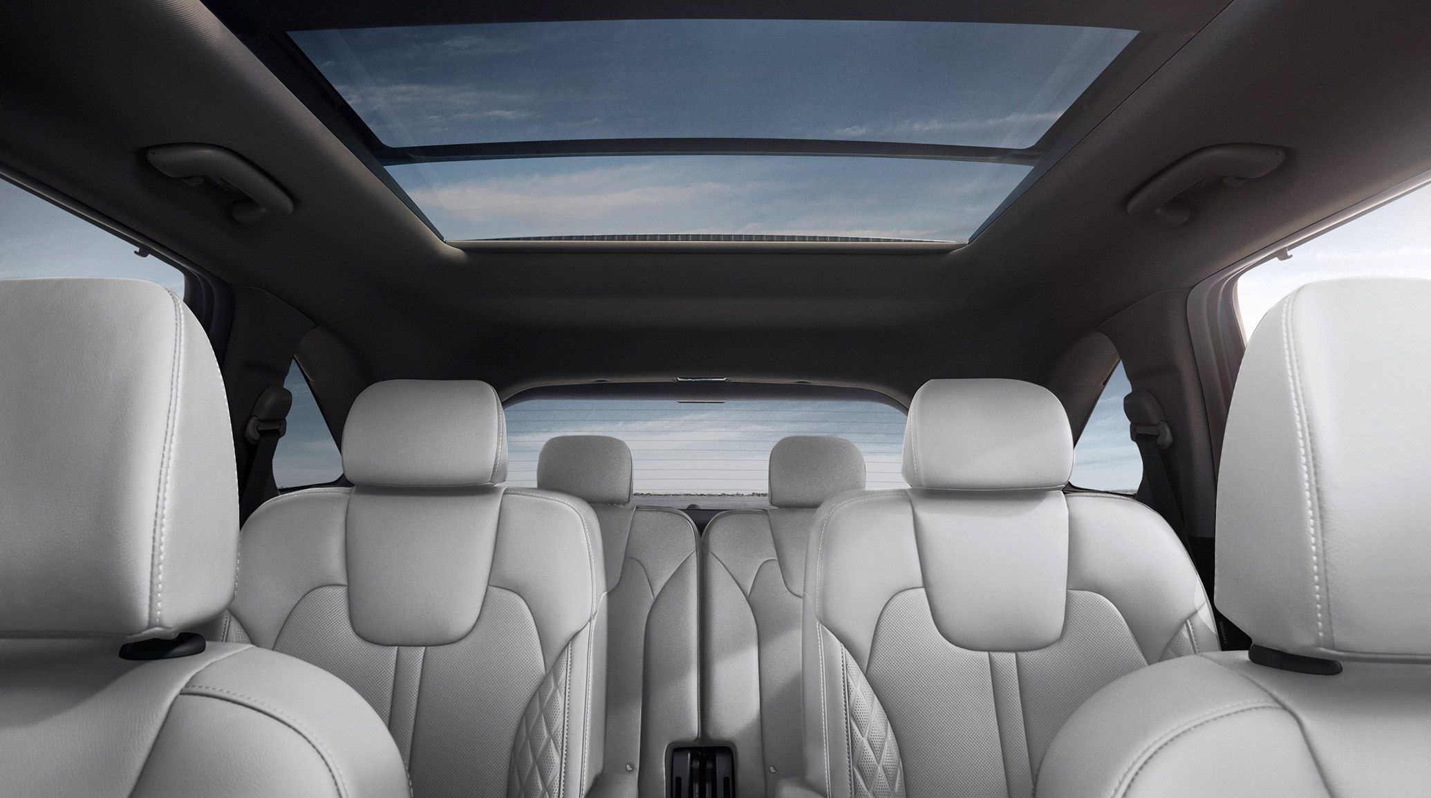 Interior shot of the 2027 Kia Sorento Hybrid SUV looking backwards at the three rows of seating in light grey, with the panoramic sunroof in view.
