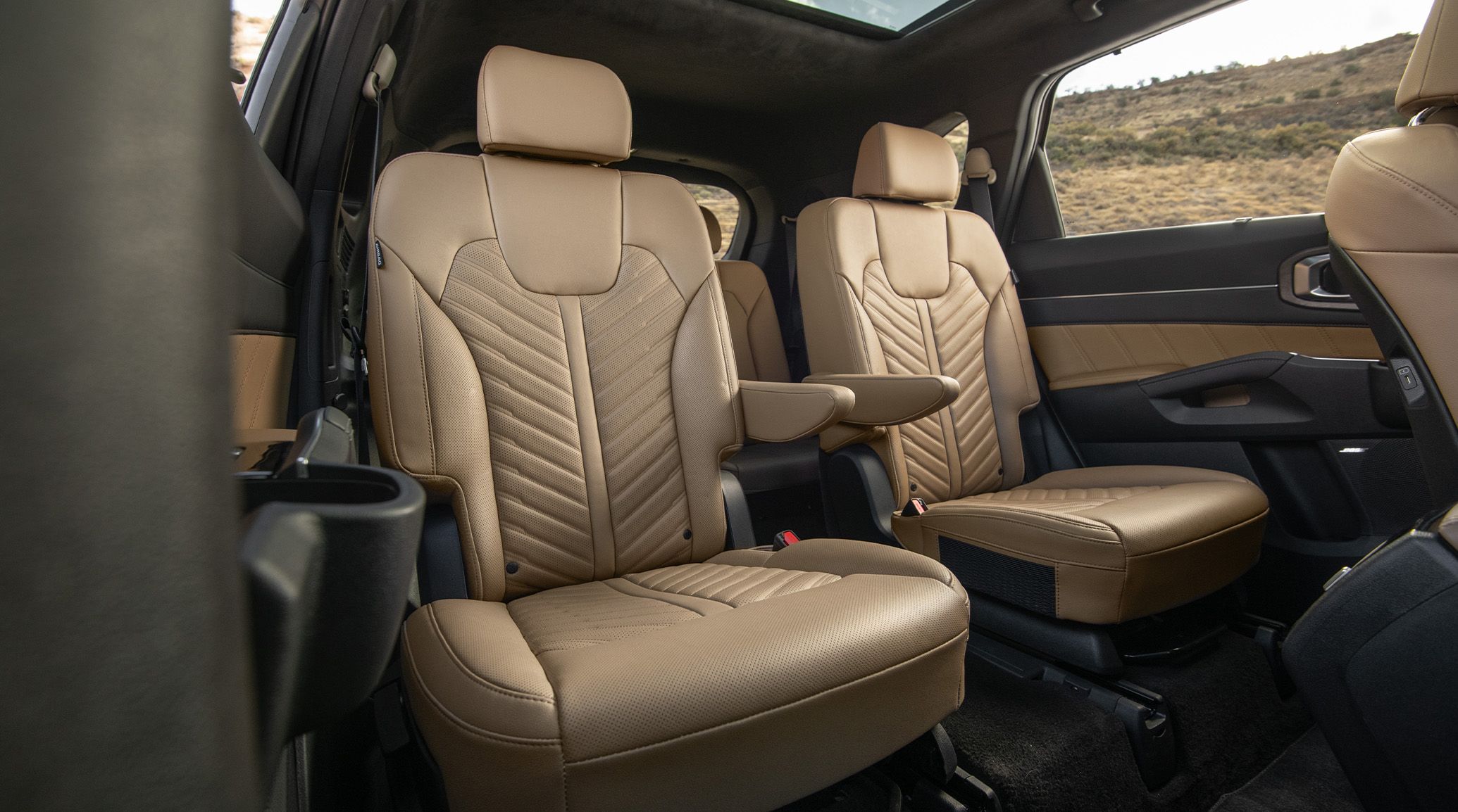 2027 Kia Sorento X-Pro SX Prestige AWD interior in brown, featuring the two comfortable second-row captain chairs with the armrests up, quilted seats, and spacious legroom.
