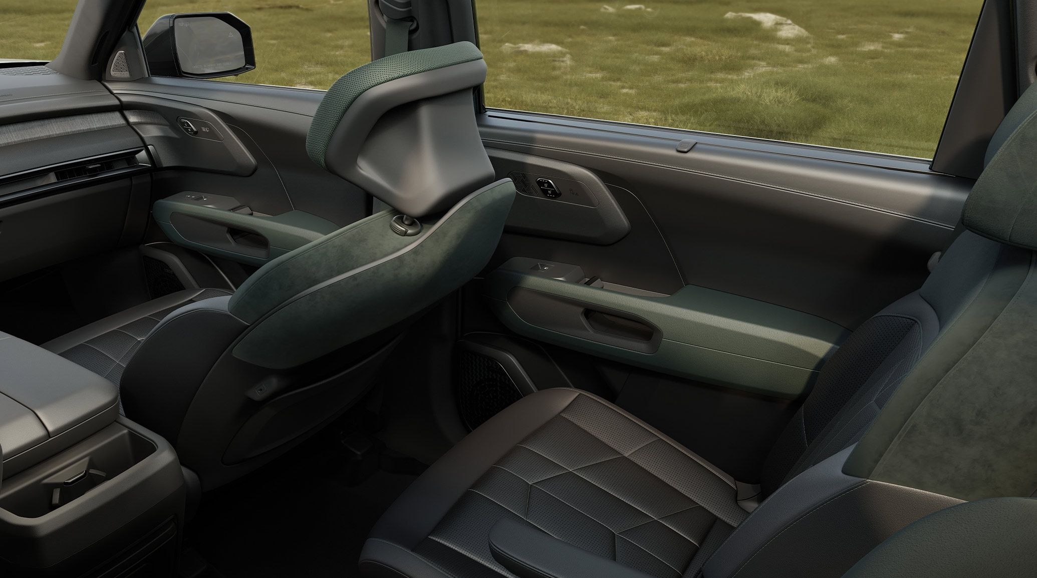 An interior shot of the 2027 Kia Telluride Hybrid showing the front passenger seat and second row suede trim seats in black with green details and adjustable headrests, with grass visible through the windows.