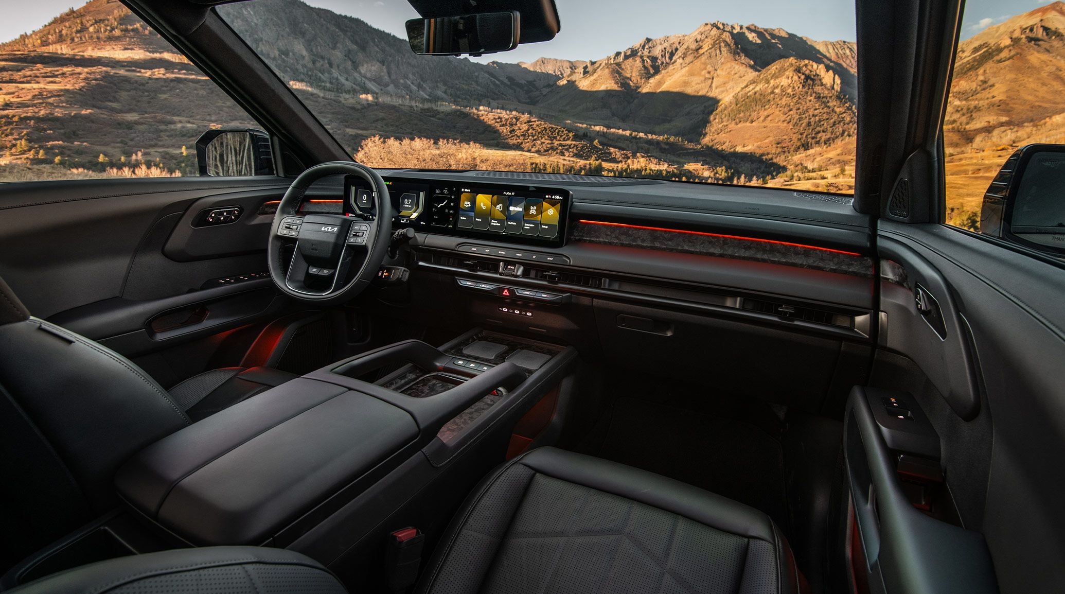 Interior shot of the 2027 Kia Telluride showcasing its black suede seats, panoramic digital display, and premium dashboard design with mountain scenery visible through the windows.