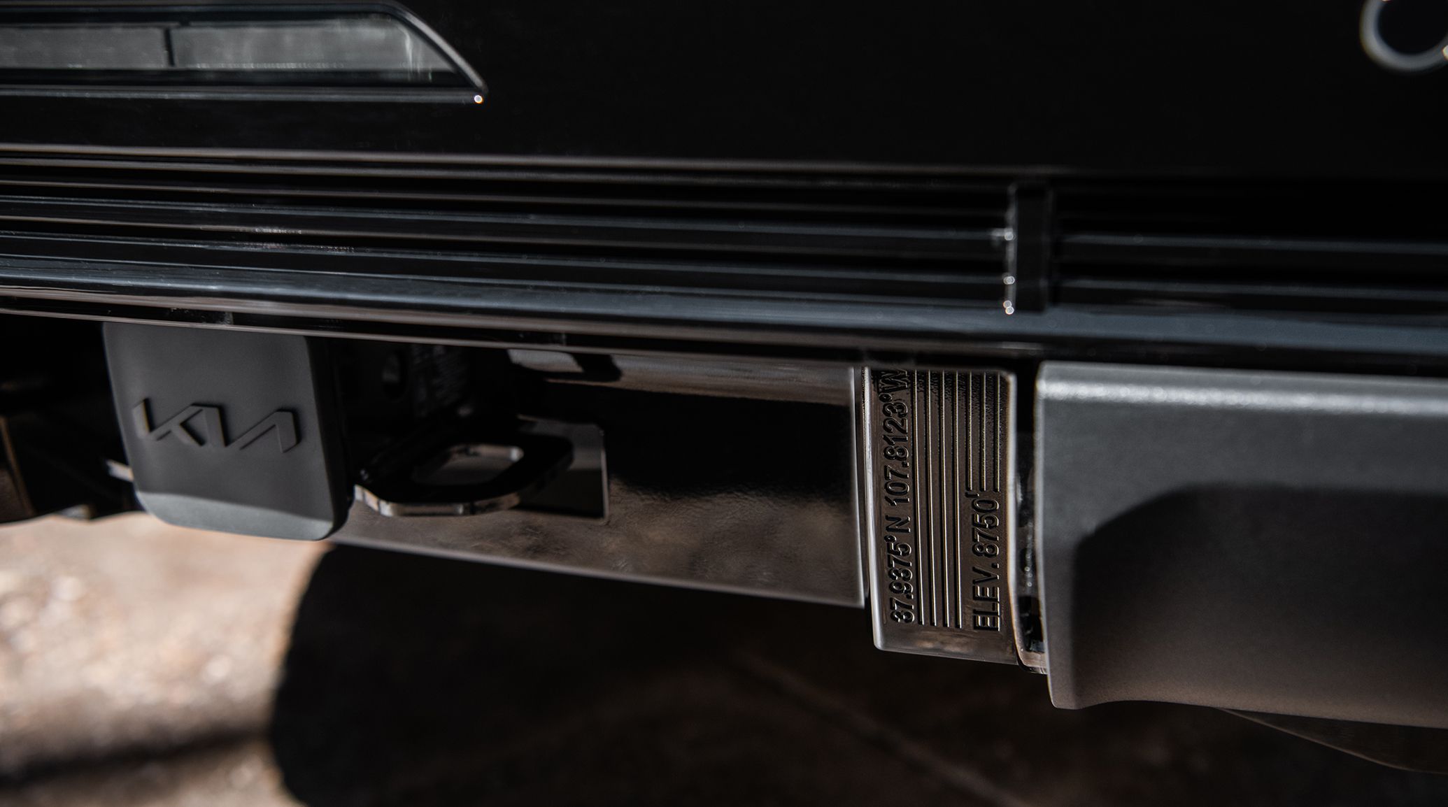 Dynamic shot of the 2027 Kia Telluride in glossy black with orange Telluride graphic accents, driving into a lake and showcasing its bold front design, signature grille, and rugged SUV design.